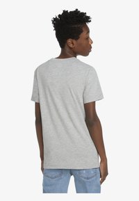Camiseta de algodón gris con mangas cortas y escote redondo, que presenta un corte relajado y una textura suave. Vista trasera sin logos visibles.