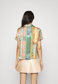 Kortærmet, multikoloreret bluse med blomster- og geometriske mønstre. Lidt løstsiddende pasform med krave. Glat, let stof.