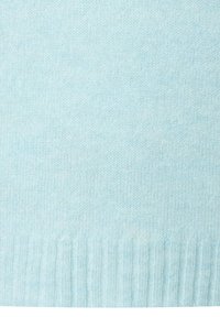 Lichtblauwe gebreide stof met ribbelstructuur aan de onderrand, die fijne garen en zachte materiaaldetails toont.