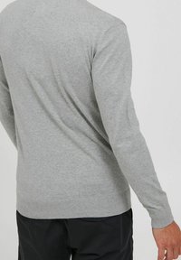 Maglione grigio lavorato a maglia visto da dietro, con maniche lunghe e orlo a coste. Texture morbida con linee pulite e senza loghi visibili.