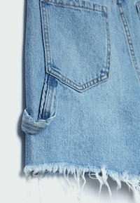 Jeanskjol i ljusblått med franskant, med fyra fickor och uppvikta ärmdetaljer. Tillverkad av texturerad bomullstyg.