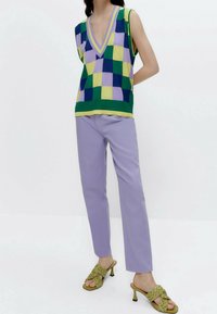 Top de punto a cuadros verde, morado y amarillo con escote en V, combinado con pantalones rectos lavanda y sandalias de tacón trenzadas en verde olivo.