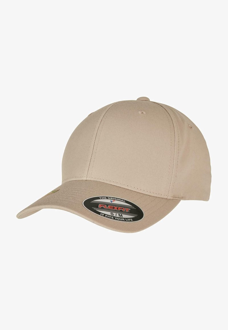 Gorra de béisbol Flexfit beige con visera curvada, diseño sin costuras y una etiqueta de logo que muestra los detalles de talla en la parte frontal.
