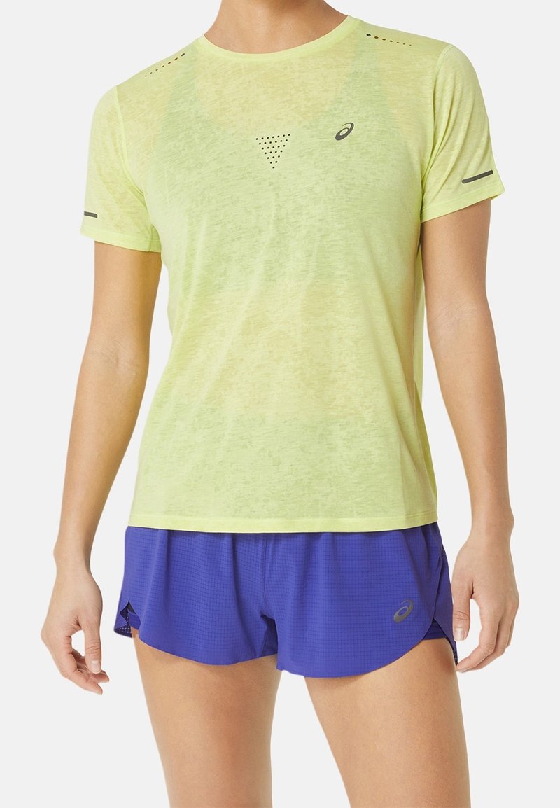 Jasnożółta sportowa koszulka z krótkim rękawem o oddychającej fakturze, wyposażona w wentylację z siateczki, w zestawie z niebieskimi, wzorzystymi spodenki do biegania.