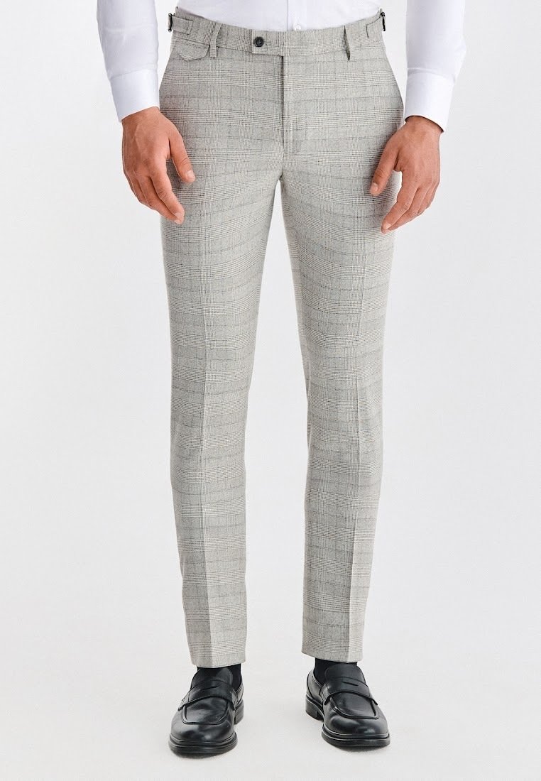 Jasnoszare spodnie w kratę o wąskim kroju, subtelnej fakturze, z pętelkami na pasek i przednimi kieszeniami, zestawione z czarnymi skórzanymi butami.