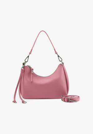 Sac à bandoulière en cuir rose avec des fermetures éclair argentées et une longue bandoulière détachable enroulée à côté sur un fond blanc.