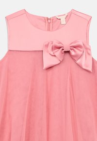 Ροζ αμάνικο φόρεμα με φιόγκο· διαθέτει διαφανές επάνω στρώμα και αδιαφανές κάτω στρώμα· κλείνει με φερμουάρ στο πίσω μέρος.