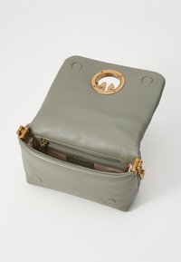 Groene leren tas met een ronde opening van goudkleurig hardware, twee binnencompartimenten en een gladde textuur. Voorzien van een magnetische sluiting en gouden accenten.