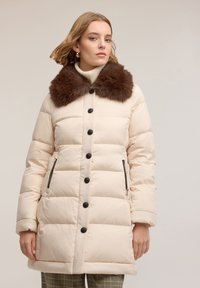 Kurtka puchowa w jasnobeżowym kolorze z brązowym kołnierzem z ekologicznego futra, z czarnymi guzikami i zasuwanymi bocznymi kieszeniami; gładka faktura, długość do kolan.