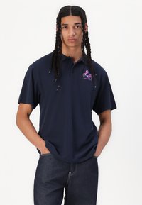 Navy polo shirt made of cotton, featuring short sleeves, a three-button collar, and a pink horse logo on the left chest.
