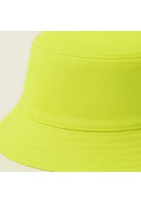 Un cappello a secchiello di un brillante giallo neon realizzato in tessuto strutturato, con tesa larga e dettagli cuciti lungo i bordi.