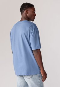 Lyseblå bomulds t-shirt med korte ærmer, rund hals og en afslappet pasform; parret med lysvaskede denimjeans.