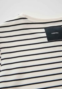 Maglietta a righe in crema e blu navy, realizzata in morbido cotone, con scollatura rotonda e un'etichetta con la scritta "un giorno" sul retro.