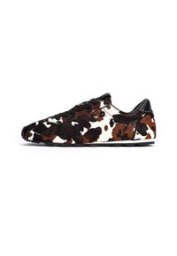 Zapato de felpa con patrón de manchas negras, marrones y blancas. Presenta cordones negros, una forma estilizada y un tacón negro texturizado.