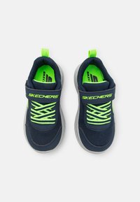 Lahe sinise värvi võrksneakersid neoonroheliste detailidega, reguleeritava rihmaga ja erksate paeltega. Paks tekstureeritud tald haarduvuse ja toe tagamiseks.