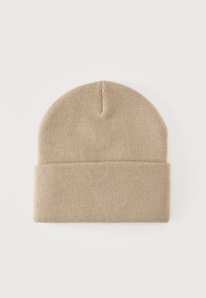 Bonnet d'hiver beige en tricot avec revers plié, posé à plat sur un fond blanc.