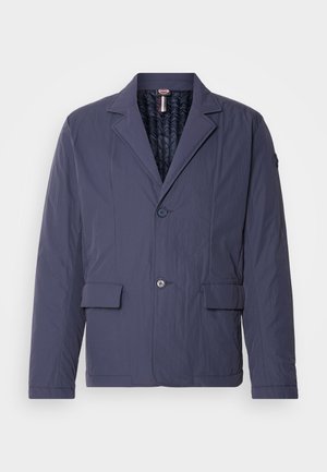 Giacca leggera di colore blu navy con finitura texturizzata, design a un solo petto, due tasche anteriori a toppa e rivestimento interno trapuntato.