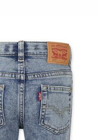 Jeans in denim azzurro chiaro con una toppa in pelle etichettata "Levi Strauss & Co. 512" in vita, dotati di due tasche posteriori e cuciture a contrasto.