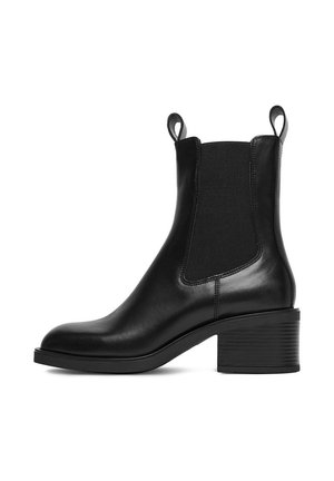Botín de cuero negro con paneles elásticos laterales, puntera redonda y tacón de bloque apilado. Cuenta con pestañas para facilitar el calzado.