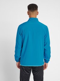 Lichte, blauwe trainingsjas met een hoge kraag, elastische manchetten en een elastische onderkant. Heeft een gladde textuur en een minimalistisch design.