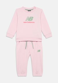 Roze New Balance peuter trainingspak met een lange mouwen top featuring logo print en bijpassende elastische broek met trekkoord en logo.