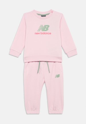 Pink New Balance toddler tracksuit with long-sleeve top featuring logo print and matching elastic-waist pants with drawstring and logo.