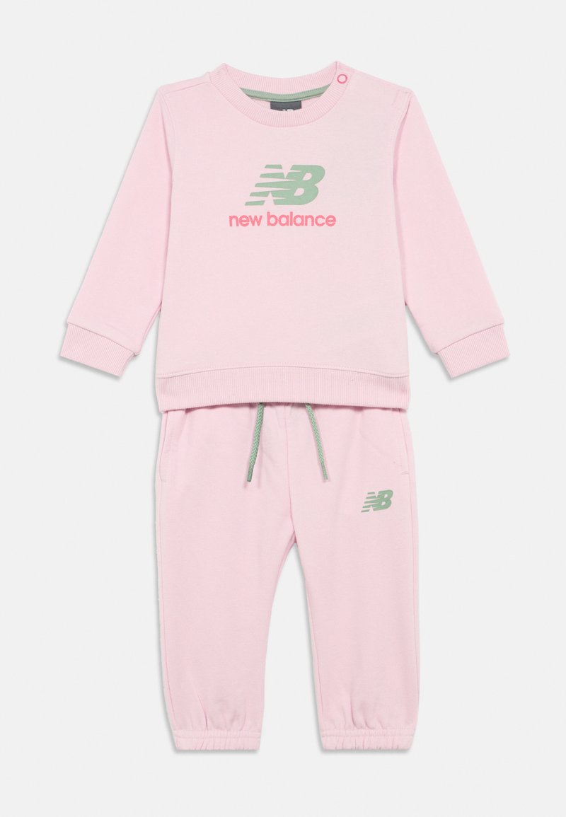 Roze New Balance peuter trainingspak met een lange mouwen top featuring logo print en bijpassende elastische broek met trekkoord en logo.