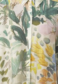 Bloemige overhemd knoopjes in lichtgewicht, doorschijnende stof met groene, gele en roze botanische patronen, voorzien van witte knopen en kraag.