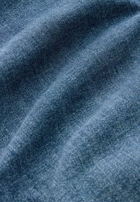 Țesătură de denim de culoare albastru închis, având o ușoară textură cu variații subtile în densitatea firului și un finisaj moale, neted.