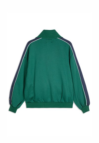 Zeleni dukserica s visokim ovratnikom, dugim rukavima, mornarsko plavim bočnim detaljima i bijelim rubovima. Mekana tekstura, opušteni kroj, elastični rub.