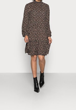 Sort midi kjole med blomsterprint, lange ærmer, høj hals og rynket kant. Kombineret med sorte ankelstøvler. Stoffet har en blød, struktureret overflade.