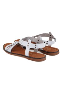 Weiße Leder-Sandalen mit geflochtenem Design, braunem gepolstertem Fußbett und dunkler Gummisohle. Mit silberfarbigen Beschlägen und verstellbaren Riemen.