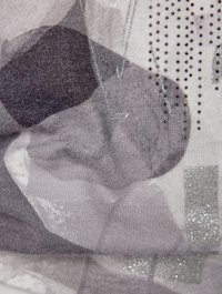 Knit textile featuring abstract gray patterns, silver accents, and a soft, textured surface. Sparkling elements add detail to the design.