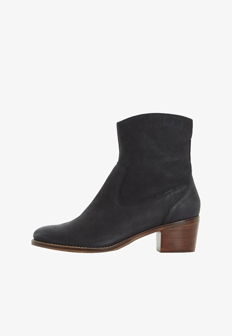 Bottine noire en cuir avec petit talon en bois empilé et bout amande, présentant des détails cousus et une texture lisse.