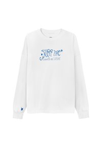 Biała koszulka z długim rękawem z niebieskim nadrukiem tekstu "SURF INC" oraz hasłem "styl życia z poparzeniem słonecznym". Posiada niebieską gwiazdkę jako akcent na rękawie.