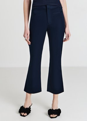 Pantaloni a vita alta blu Navy con vita aderente, tasche frontali e orlo svasato. Abbinati a sandali neri con fantasia floreale e fascia aperta. Tessuto liscio.