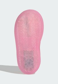 Pink translucent sole of a sandal showing a herringbone tread pattern with a curved line and embedded smiley face design.