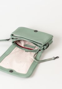 Lichtgroene leren schoudertas open, met een beige patroon binnenin en een rode ritszak en een afneembare strapclip.