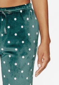 Pantalon de pyjama en velours teal avec des pois blancs, doté d'une taille élastique et d'un cordon de serrage, texture lisse et design décontracté.