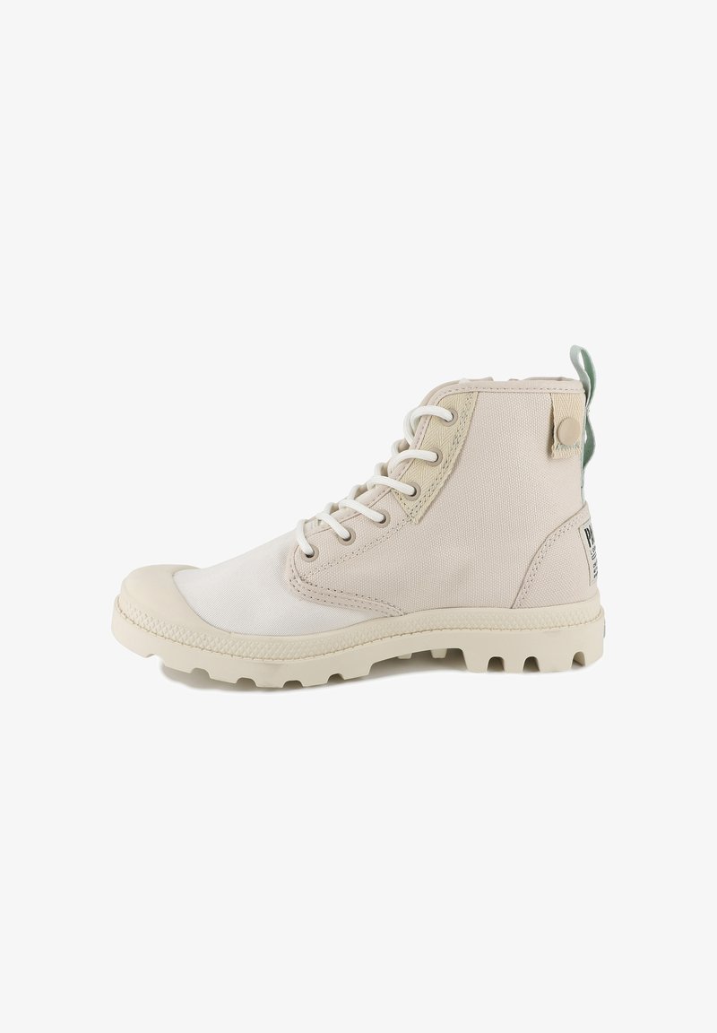 Bottine beige en toile avec embout en caoutchouc, lacets blancs, accents texturés et languette de tirage verte à l'arrière ; semelle extérieure résistante avec crampons.
