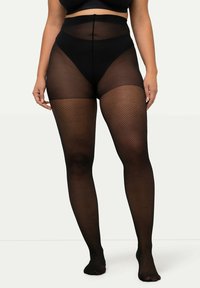 Collant in rete nera con vita alta. Materiale trasparente sulle cosce, motivo a diamante testurizzato e design con punta. Finitura liscia complessiva.