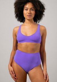 Lila tvådelad bikini med en tajt, texturerad crop top med breda band och högmidjade underdelar. Slät tyg och enkel design.