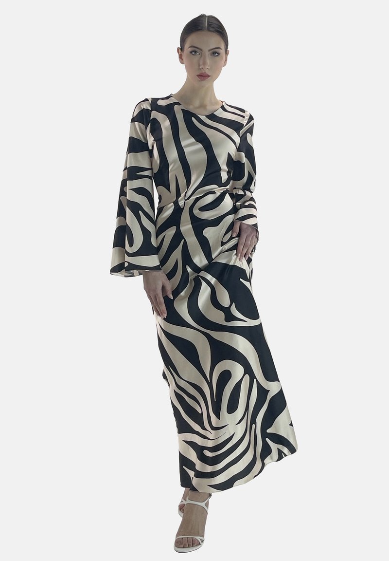 Robe longue en satin présentant un motif tourbillonnant noir et crème, avec des manches évasées et une silhouette ajustée, complétée par des talons avec des lanières.
