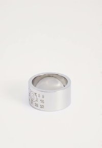Wide silver ring with embossed numbers and a circled "S" on a plain white background.