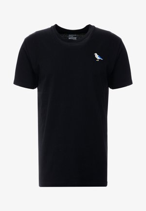 Schwarzes Baumwoll-T-Shirt mit kurzen Ärmeln, Rundhalsausschnitt und einem kleinen bestickten Vogel in Blau und Weiß auf der linken Brustseite.