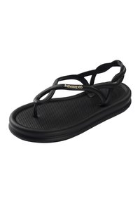 Μαύρο σανδάλι Havaianas με υφασμένη σόλα και λεπτά διασταυρωμένα λουράκια, με χρυσό λογότυπο Havaianas στο μπροστινό λουρί.