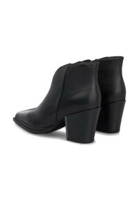 Par de botas negras de cuero hasta el tobillo con tacones de bloque apilados y cremalleras laterales sobre un fondo blanco.