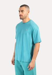 Turfärgad bomullströja med kort ärm, rund hals och liten logodetalj. Avslappnad passform och slät textur.