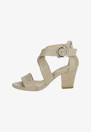 Beige hoge haksandalen met kruislagen, verstelbare gesp en een gestructureerde blokhak. Glad leer met subtiele stiksels.