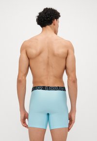 Helle blaue Boxershorts mit einfarbigem Design, elastischem schwarzen Bund, der "LOUR" zeigt. Glatte Textur, mittellanger Schnitt und taillierte Passform.
